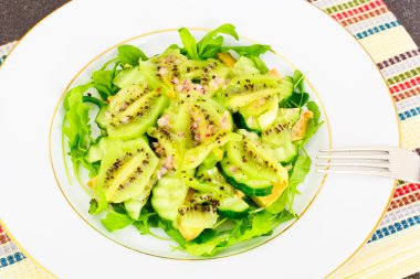 Roka Salatası, kivi ve salatalık beyaz plaka üzerinde