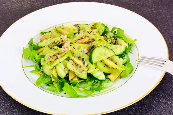 Rucola salade, kiwi en komkommer op witte plaat — Stockfoto