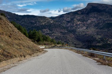 Dar, dağlık, kırsal bir yolda, bulutlu bir kış gününde 