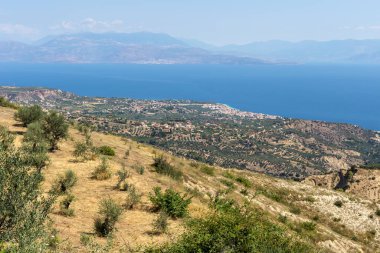 Yüksek dağların, köyün ve engin denizin panoramik manzarası güneşli bir bahar günü (Yunanistan, Mora)