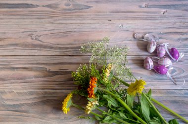 Paskalya kompozisyonu. Yumurtalar ve bir buket renkli gerberalar ahşap masa üzerinde yakın plan.