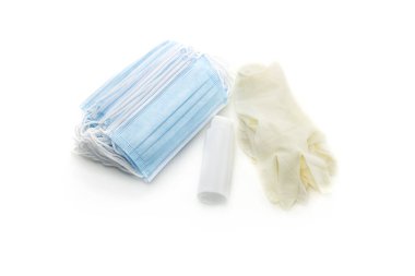 Tıbbi maskeler, tek kullanımlık eldivenler ve beyaz arka planda bir şişede antiseptik.