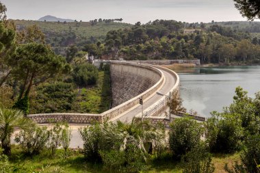 Güneşli bir bahar gününde, Maraton (Yunanistan) gölü kıyısındaki taş köprü ve dağların manzarası