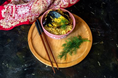 Deniz ürünleri. Ahşap tepside baharatlı, sebzeli ve çubuklu midyelerden yapılan pilav.