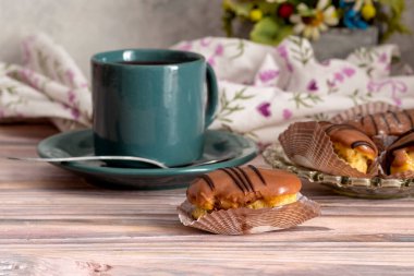 Bir tabakta üç taze, lezzetli kek ve ahşap arka planda bir fincan çay.