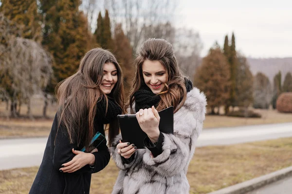 Dos hermosa chica con una tableta en el parque de otoño —  Fotos de Stock