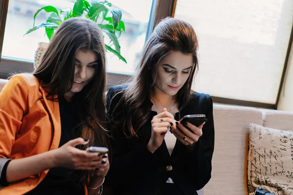 Two beautiful girls in cafes phones — Stock Photo, Image