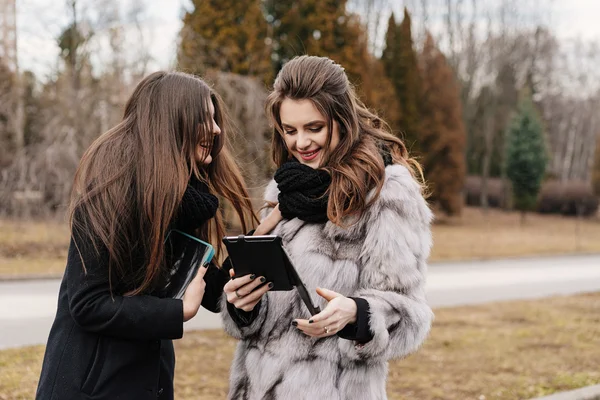 Dos hermosa chica con una tableta en el parque de otoño —  Fotos de Stock