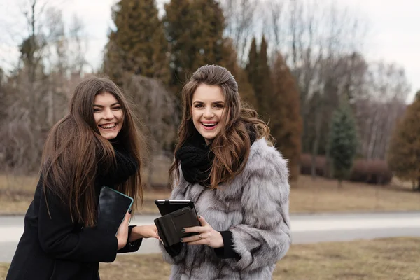 Dos hermosa chica con una tableta en el parque de otoño —  Fotos de Stock