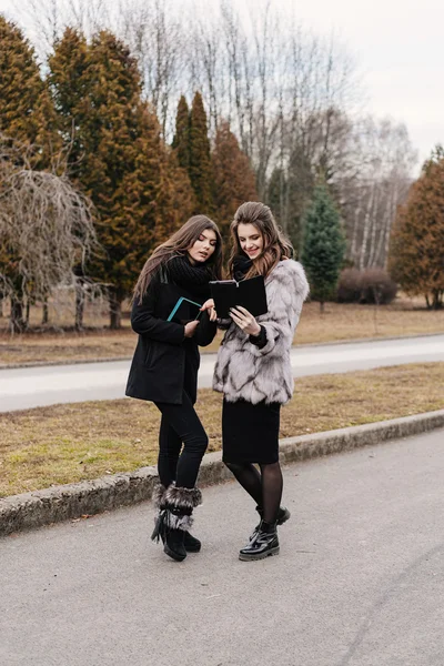 Zwei schöne Mädchen mit einem Tablet im Herbstpark — Stockfoto