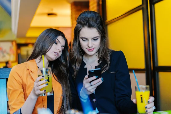 Dos hermosas chicas en cafés teléfonos —  Fotos de Stock