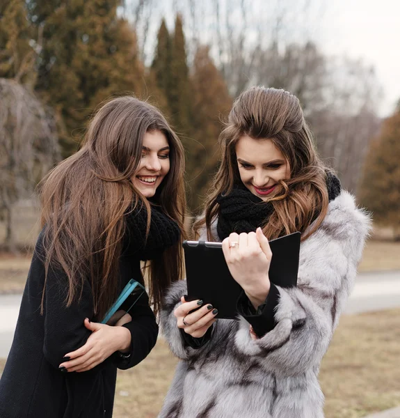 Dos hermosa chica con una tableta en el parque de otoño —  Fotos de Stock