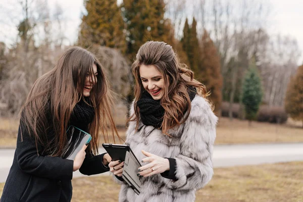 Dos hermosa chica con una tableta en el parque de otoño —  Fotos de Stock