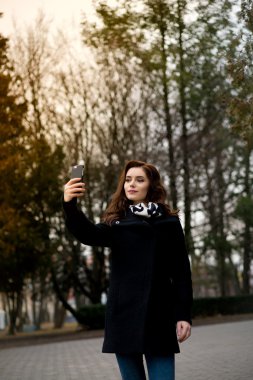 Güzel genç kadın selfie parkta yapar.