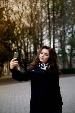 Güzel genç kadın selfie parkta yapar.