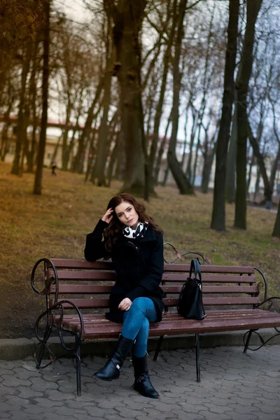 Menina bonita sentada em um banco de parque — Fotografia de Stock