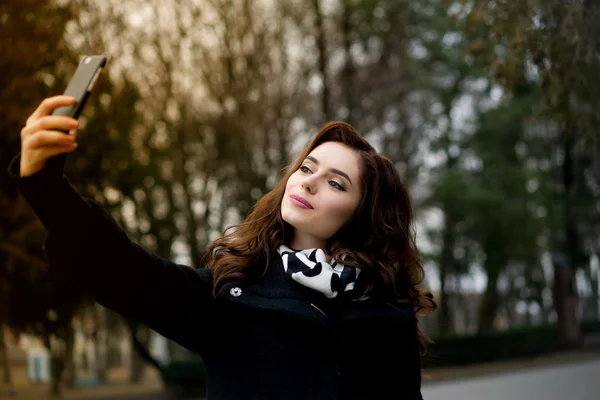 Schöne junge Frau macht Selfie im Park — Stockfoto