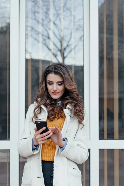 Beautiful girl with a phone in town — Stock Photo, Image