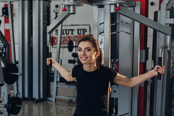 La chica en el gimnasio en un simulador — Foto de Stock