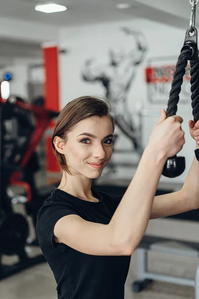 Hermosa chica en el gimnasio en un simulador — Foto de Stock