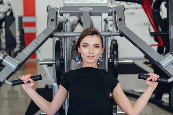 La chica en el gimnasio en un simulador — Foto de Stock