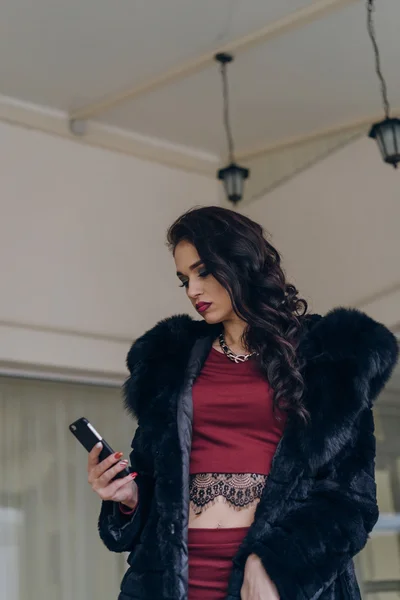 Elegantes Modell in schwarzem Mantel mit Telefon — Stockfoto