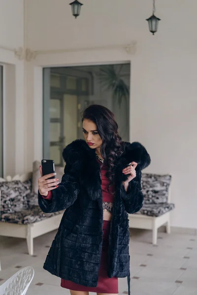 Елегантна модель в чорному пальто з телефоном — стокове фото