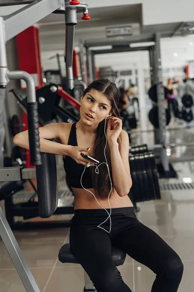Hermosa chica con un teléfono en el gimnasio — Foto de Stock