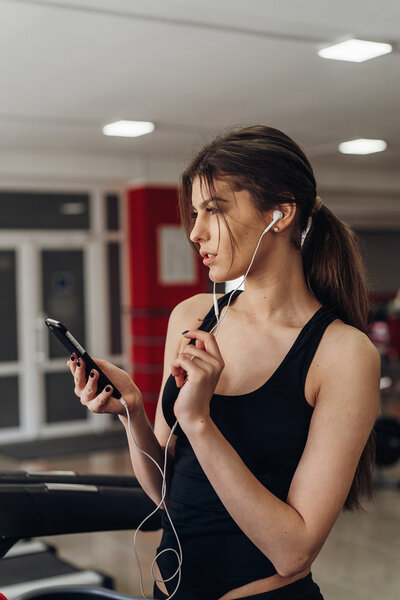 Beautiful girl with a phone in the gym