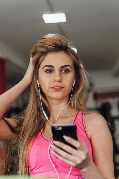 Sarışın spor salonunda bir telefon ile. Müzik
