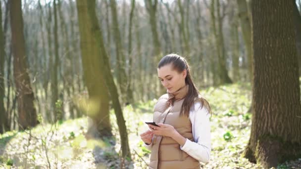 Mladá dívka mluví po telefonu v lese. 4k — Stock video