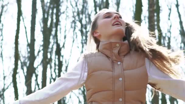 Belle fille sautant dans une forêt printanière ensoleillée. Doucement. 