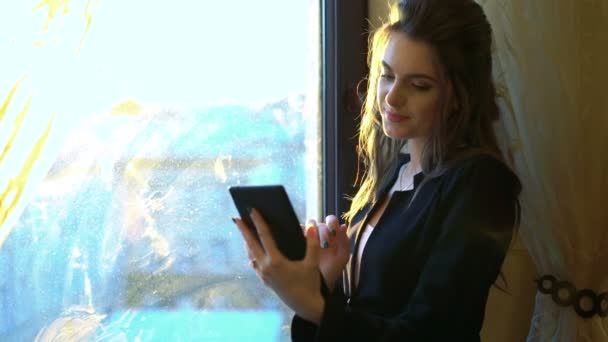 Бизнес-леди со смартфоном на фоне окна и штор — стоковое видео