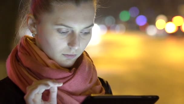 Close-up meisje permanent op straat in de nacht met behulp van Tablet PC. Langzaam. — Stockvideo