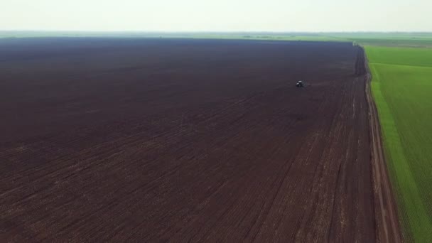 Luchtfoto van velden, trekker ploegen van de bodem in de lente — Stockvideo