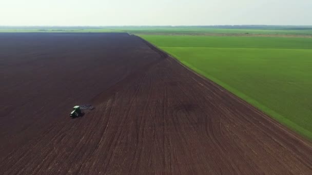 Luchtfoto van velden, trekker ploegen van de bodem in de lente, op een afstand houden — Stockvideo