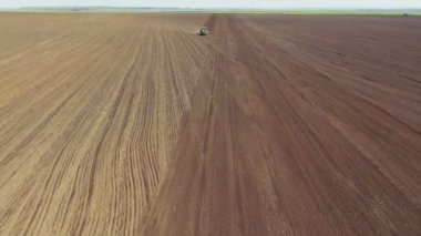 Toprak sahada güneşli bahar günü çiftçilik traktörün havadan görünümü