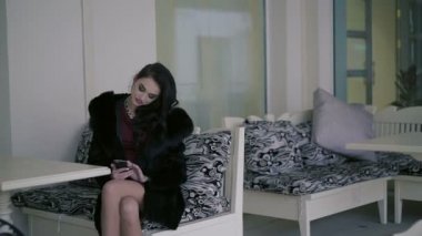 Telefonunuzun ve kafede ve gülümseyen mutlu seductively genç kadın