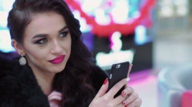 Masada oturan ve smartphone kullanarak zarif kadın. Yavaş yavaş