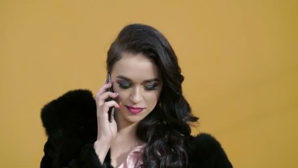 Elegante Frau mit blauen Augen im Pelz, die auf dem Smartphone spricht — Stockvideo
