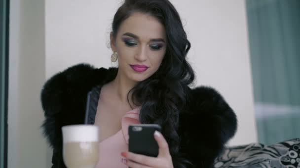 Glamorosa dama bebiendo café con leche seductora, usando el teléfono en la cafetería — Vídeo de stock