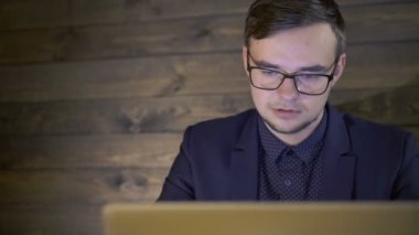 Kafede oturan ve bir dizüstü bilgisayar kullanarak zarif işadamı