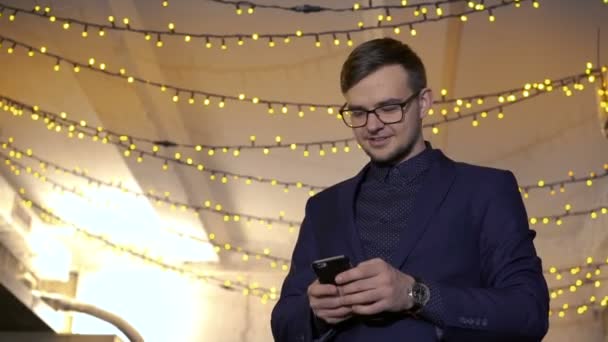Elegant man using phone on the background of a lights — Stock Video