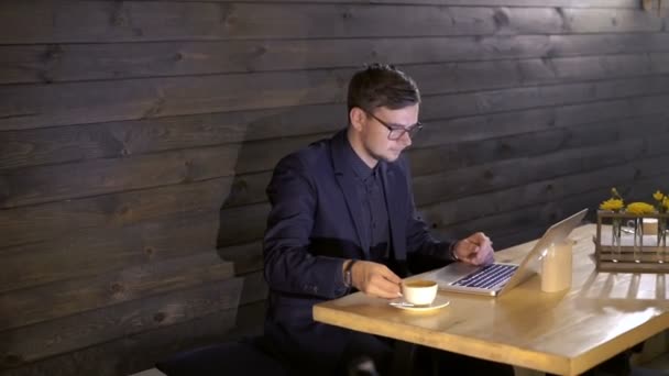 Elegante homem de negócios trabalhando com um laptop e beber café no café — Vídeo de Stock