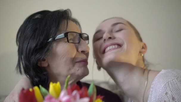 Nieta con la abuela sosteniendo flores y sonriendo en la cámara. Despacio. — Vídeos de Stock