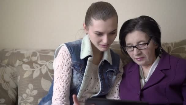 Niña aprendiendo mujer mayor cómo usar la tableta . — Vídeos de Stock