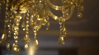 Parlak bir arka plan üzerinde altın kristal bir avize sarkacak. Ağır çekim