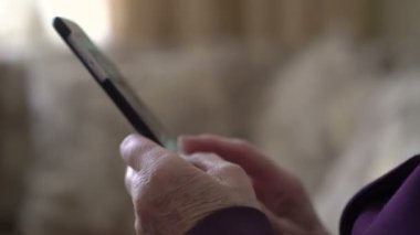 Yaşlı kadının elinde kırışıklıkları bir pencere arka plan ile Smartphone