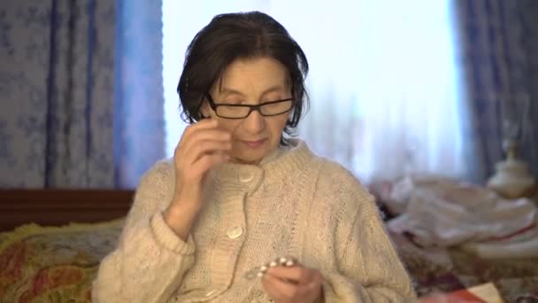 Old woman wearing glasses, holding medicament and looking — Stock Video