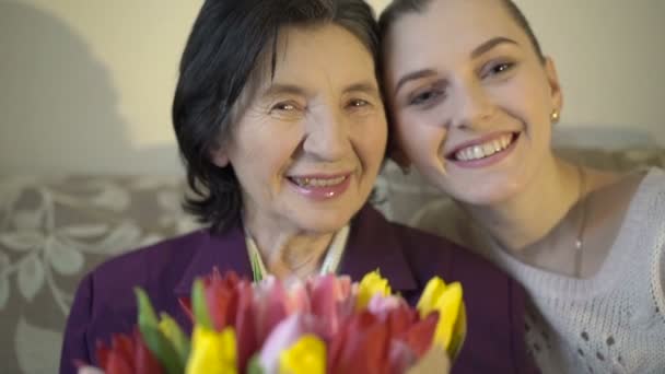 Oma met bloemen en kleindochter glimlachend op de camera. Langzaam — Stockvideo